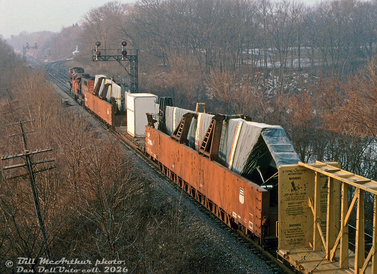 CN train 393 rolls through Bayview Junction in the morning with two special loads up front: a pair of Union Pacific "wing gondola" cars carrying two large airplane wing assemblies built at the Boeing/McDonnell-Douglas plant in Malton, bound for their assembly plant in Long Beach, California. The train, with three CN GP40-2W or SD40-2W units for power, is seen taking the crossover in order to head up the Dundas Sub, ultimately bound for the US.A unique car for a unique operation:In the 1960's, McDonnell-Douglas Canada, who was operating the old A.V.Roe (Avro Arrow) plant in Malton (originally opened by National Steel Car in 1939 as their aircraft division, later sold to the government during WWII), needed a bigger car to ship wing assembles for the new DC-10 model from their Canadian branch plant in Malton to their Long Beach, California plant for final aircraft assembly. They purchased 6 unique 88-foot long "wing gondola" cars from Maxson in 1969 (DCCX 1001-1006) and began shipping DC-10 wing assemblies in them, and Union Pacific followed up with an 8 car order in 1971 (UP 229580-229587), likely due to increased DC-10 production.Both groups of cars were used in pool service between Malton and Long Beach, shipping completed wing assembles from the "MDCan" Malton factory in Canada down to California for final assembly, and empty cars forwarded back. They were typically shipped out in pairs (one left wing, one right), with an idler flatcar equipped with a container full of wing assembly parts separating them. Research indicates the smaller wing assemblies (DC-9) being built at the Malton plant went out on flatcars, the larger assemblies (DC-10, MD-11) were shipped out on wing gondolas. CN switched the cars out of MD's plant off Airport Rd via a long spur off the Weston Sub near Malton GO station, that passed through the grounds of De Havilland's old Malton plant (later the International Centre, that featured a retractable walkway between convention buildings to let MD cars pass through). Sometimes they could be found spotted on sidings in the Malton area near the plant, including around the former Malton Station (Scarboro Rd), by Woodbine Racetrack (Woodbine East), and Malport where freights to the US via Sarnia would sometimes lift them.Intelligence suggests routing was CN from Malton to GTW (via Port Huron) to Rock Island (interchanged at Blue Island in Chicago) to UP (interchanged at Council Bluffs, Iowa) for their final trip to Long Beach CA. There's even a photo out there of three Rock Island passenger E8A's hauling a freight train through the US midwest with a pair of wing gondolas heading back to Malton in-consist.This operation continued after Boeing bought McDonnell-Douglas in 1997. Being this is a 1999 photo, production indicates these are either Boeing MD-11 or MD-80 wing assemblies, or possibly those for the then-new 717. Apparently around 2000, they started shipping wing assemblies out by truck and discontinued the use of wing gondolas. Following the last shipment of 717 wings the Malton plant was closed by Boeing in 2005 and was demolished, and the Long Beach plant appears to have been initially closed in 2006 after completion of the last 717, but continued producing military C17's until 2015. Some indicate a bunch of the DCCX wing gondolas were scrapped by CN in the early 2000's at the south end of MacMillan Yard, and some of the UP cars may have gone into MofW service.Bill McArthur photo, Dan Dell'Unto collection slide.More wing gondola loads:Ground-view at Bayview Junction: http://www.railpictures.ca/?attachment_id=40429Returning empty through Burlington: http://www.railpictures.ca/?attachment_id=18567MD spur switch in Malton near Orenda Engines: http://www.railpictures.ca/?attachment_id=36986
