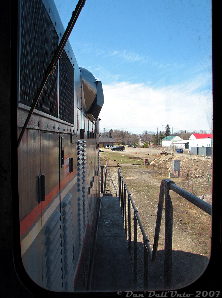 Here's the long-hood forward view while riding aboard Orangeville-Brampton Railway's CCGX 1000, a 1957 GMD-built GP9, as it runs around Orangeville Yard after completing its twice-weekly run to Streetsville and back. After dropping its lone car off in the yard, it was then filled up by local fuel dealer Bryan's Fuel and received some some light servicing from the engineer and conductor. Then the unit was moved around the yard and onto the station track to tie down on the Credit Valley Explorer's passenger equipment, effectively being put away for the day. In the distance is the OBRY's new Orangeville Station, and on the right is the site of the former CPR bunkhouse that burned down a few years prior. Another big thanks to Conductor Steve and Engineer Wayne for the short cab ride.

The GP9 was designed to be a bidirectional roadswitcher locomotive, but still had controls installed oriented for one end to lead or be designated the "front" of the unit. Dating from steam era practices, many railroads in the 1940's and 50's ordered their new diesel locomotives oriented for long-hood forward operation, putting the diesel engine and main generator in front of the crew and cab. One reason was for better accident protection in the event of a level crossing or head-on collision, another was crew familiarity after operating steam engines like this for so long. This practice gradually switched during the 50's and 60's as locomotives with low short hoods and better visibility became more popular. Quebec, North Shore and Labrador, Ontario Northland, and Canadian Pacific all ordered their Canadian-built GP7/GP9 units oriented for short hood forward operation, but Canadian National purchased their entire fleet as long-hood forward units. This would have been the view for a CN engineer for many decades operating a GP7/GP9, RS3/10/18 and other first generation diesels on mainline freights (even today, the 7000's and 7200's still have the controls oriented for long-hood forward operation).