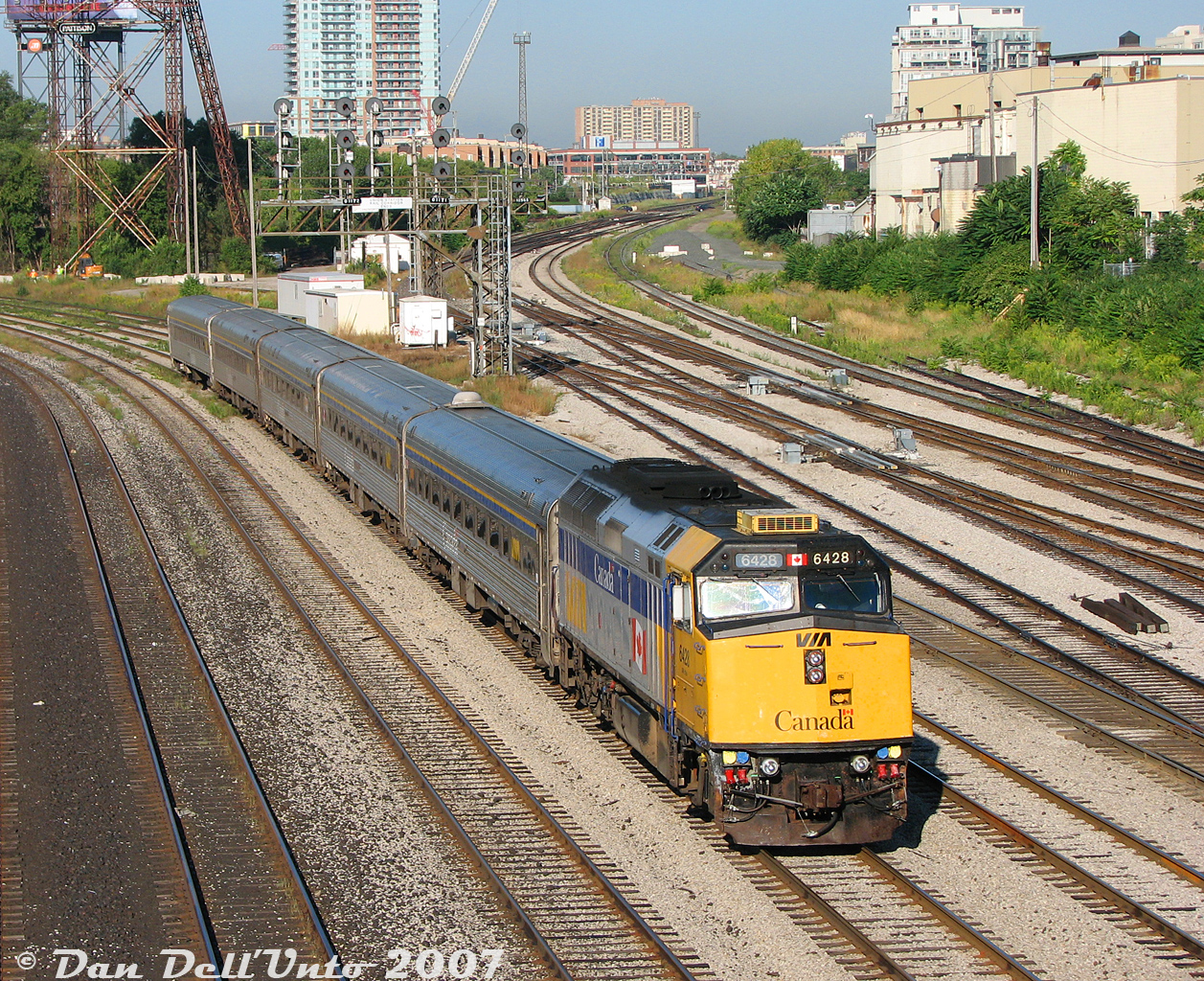 After completing its inbound run off the Weston Sub on VIA Rail train #86 (London-Toronto, big yawn for its early 5:20am departure to 8:13am arrival), F40PH-2D 6428 backs its consist of five Budd HEP2 coaches through Bathurst Street on a sunny morning back to the Toronto Maintenance Centre in Mimico. Typical of the era was the yellow add-on rooftop air conditioner (a few units were still running around without one). "Flap open" was normal for about half the VIA F40's you'd see on any given day until the rebuild program did away with that pesky flap by relocating the front MU plug to the pilot. Note the replacement numberboard on the engineer's side, the original possibly a victim of an errant bird while at speed.