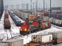 It was the day of the annual Toronto-area Christmas train show, held every November down at the Mississauga International Centre, but before pleasure there was business to attend to in Brampton: There had been a then-rare GMD-1 regularly assigned to the Brampton Intermodal Terminal set for switching the yard, and like Scooby Doo and the gang, we needed to go down and catch it.<br><br>Departing around noon, after a visit to shoot a train on the BIT pullback track pulled all the way to Automatic Drive, the next stop was a visit to the Highway 7/Queen Street overpass. There was our target GMD-1 1423, visible in the yard but tucked away with her GP9RM-slug set on a track in the distance not doing anything (8-ball says crew lunch break). Since we weren't getting any action along Queen, a side-trip was made to the Malport Yard area to shoot <a href=https://www.railpictures.ca/?attachment_id=59663><b>CN #577</b></a> and <a href=https://www.railpictures.ca/?attachment_id=9283><b>#393</b></a>, before doing some other shenanigans (probably lunch) and heading back to BIT for another look.<br><br>Sure enough, CN 1423 with slug 242 and mother GP9RM 7265 were busy drilling cuts of intermodal cars at the north end of the yard, as other mainline trains yarded and did their switching. If this looks like a busy scene, it was - as CN's main Toronto-area container terminal, BIT is usually busy. Some photos were had, as 1423 had the significance of being the first GMD-1 built (<a href=http://www.railpictures.ca/?attachment_id=36814><b>CN 1000</b></a>), before entering the late 80's rebuild program and emerging as GMD-1B 1423 (it's now preserved by the CRHA out west). One of the neat things about shooting off Highway 7 is you can see part of Pearson Airport and the Brampton-Mississauga hydro corridor towers in the distance. Unfortunately was also really really cold and windy on that overpass, so this shot was not without sacrifice to the comfort of gloveless extremities.