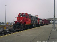 "That's not my GO train, where do I tap the Presto on this thing?!?!"<br><br>One redeeming feature of the chaos at Bramalea GO station was it would occasionally drop random CN trains like this out of nowhere into your lap. Waiting for a morning GO train? Here's a CN local finishing work around Brampton to shoot, or a GEXR export special with 10 brand new Class 66's fresh from London (that one actually happened). Witness CN GP38-2 4700 and GP9RM 4110 in matching zebra stripes showing up at 7:46am and slowly crawling through the morning fog, heading eastbound through Bramalea GO on track #2 with a sizable local in tow past everyone waiting for the next Toronto-bound GO train to appear. Usually the local working this area went through the other way in the mornings, so I can only speculate this was an overnight or early morning #578 that had finished switching some Brampton/Bramalea industries and was making its way back to Malport amid the morning GO rush, likely waiting for a gap in traffic so the RTC could give it the light through Halwest and into Malport Yard.<br><br>CN 4700 (ex-5500, the class unit) in ratty zebra stripes was a regular on the locals in the area at the time. Around 2007 it would depart and return in a <a href=http://www.railpictures.ca/?attachment_id=284><b>fresh coat</b></a> of the modern CN "website" livery.<br><br>The crossbucks and weird railing setup next to 4700 were to corral the "Bramalea Marathon" runners safely over the unused Kuehne & Nagel siding by the south GO parking lot, known for multiple daily parking violations as spots filled up during the course of the day ("Fire route? Sorry, I need to catch the York University GO bus in 3 minutes or I'm late for that business finance exam at Schulich!"). More recent south parking lot renovations suggest this was all done away with, as most of the siding had been removed prior.
