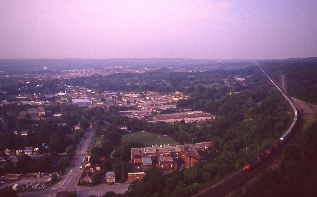 There was a time when I had a day off I just could not sit still and had to get trackside to see what was happening.  On this particular day I found myself up on Dundas Peak before it was even daylight; and after a short wait of about 45 minutes I see a headlight. Eastbound.
With the old film camera it was not easy to get a decent shot in early daylight conditions seeing there is so much shadow along the line.
So, decided to incorporate a lot of the town of Dundas into the view and the results came out not too bad. CN 5030 is the leader on this train, followed by what I can tell is 9510 and a sister. Not sure on the 4th.
Shooting from this location is pretty much a thing of the past. Too complicated to talk about here, but I think it involves a steep fee, reservations, shuttle and restricted hours.  That's enough to scare me away.