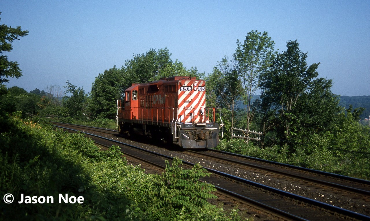 Trundling east from Guelph Jct, the CP “Stone Train” with solo 8205 negotiates the many curves east of the Kelso ski hill as it descends the Niagara Escapement heading to Streetsville, Ontario on the Galt Subdivision. The GP9u, minus a caboose today, was able to get out of the junction amongst the weekday morning eastbound parade of five empty GO Transit sets that would also head eastbound to Milton to load daily commuters for trips into Toronto.