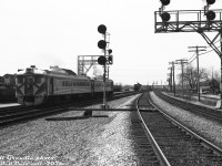 After making their stop at CN's Burlington Station, CP Rail RDC-2 cars 9115 and 9103 pull out of the station on CP train #321 (the CP-TH&B-PC Budd run from Toronto to Buffalo NY), heading westbound on CN's Oakville Sub. Photographer Bill Grandin is standing next to the two mainline tracks of the CN <a href=https://www.railpictures.ca/?attachment_id=58421><b>Halton Sub</b></a> (on the right, former CN Milton Sub), that connected to the Oakville Sub here at CN "Burlington" (later renamed "Burlington West"). Some freight cars are visible on the back tracks around the station area to the left, along with part of the Niagara Brand Chemical plant (later Reichhold Ltd./Sun Chemical). Track diagrams show the siding on the right off the Halton Sub was for Tip Top Canners Ltd. (owned by Stuart House).<br><br>For decades, CP ran freight and passenger traffic over the CN Oakville Sub between Toronto and Hamilton Junction via a trackage right agreement. This agreement dated from the Grand Trunk Railway granting it to the CP in 1896, and also included interswitching rights to customers along the line. Some speculate this was to avoid the extra competition from a potential new railway line operated by the TH&B (CP), who were considering building their own parallel line just to the north of CN's. In any case, the new TH&B line was never built, and CP's trackage rights over this stretch lasted until 2009, and weren't renewed.<br><br>Same train pulling up to Burlington Station: <a href=https://www.railpictures.ca/?attachment_id=59468><b>https://www.railpictures.ca/?attachment_id=59468</b></a><br><br><i>Bill Grandin photo, Dan Dell'Unto collection negative</i>.