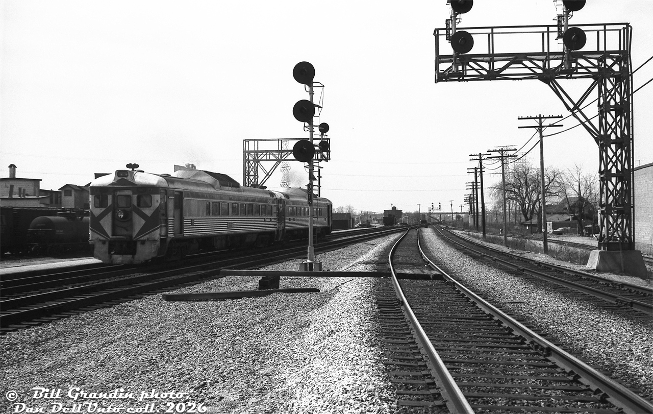 After making their stop at CN's Burlington Station, CP Rail RDC-2 cars 9115 and 9103 pull out of the station on CP train #321 (the CP-TH&B-PC Budd run from Toronto to Buffalo NY), heading westbound on CN's Oakville Sub. Photographer Bill Grandin is standing next to the two mainline tracks of the CN Halton Sub (on the right, former CN Milton Sub), that connected to the Oakville Sub here at CN "Burlington" (later renamed "Burlington West"). Some freight cars are visible on the back tracks around the station area to the left, along with part of the Niagara Brand Chemical plant (later Reichhold Ltd./Sun Chemical). Track diagrams show the siding on the right off the Halton Sub was for Tip Top Canners Ltd. (owned by Stuart House).

For decades, CP ran freight and passenger traffic over the CN Oakville Sub between Toronto and Hamilton Junction via a trackage right agreement. This agreement dated from the Grand Trunk Railway granting it to the CP in 1896, and also included interswitching rights to customers along the line. Some speculate this was to avoid the extra competition from a potential new railway line operated by the TH&B (CP), who were considering building their own parallel line just to the north of CN's. In any case, the new TH&B line was never built, and CP's trackage rights over this stretch lasted until 2009, and weren't renewed.

Same train pulling up to Burlington Station: https://www.railpictures.ca/?attachment_id=59468

Bill Granding photo, Dan Dell'Unto collection negative.