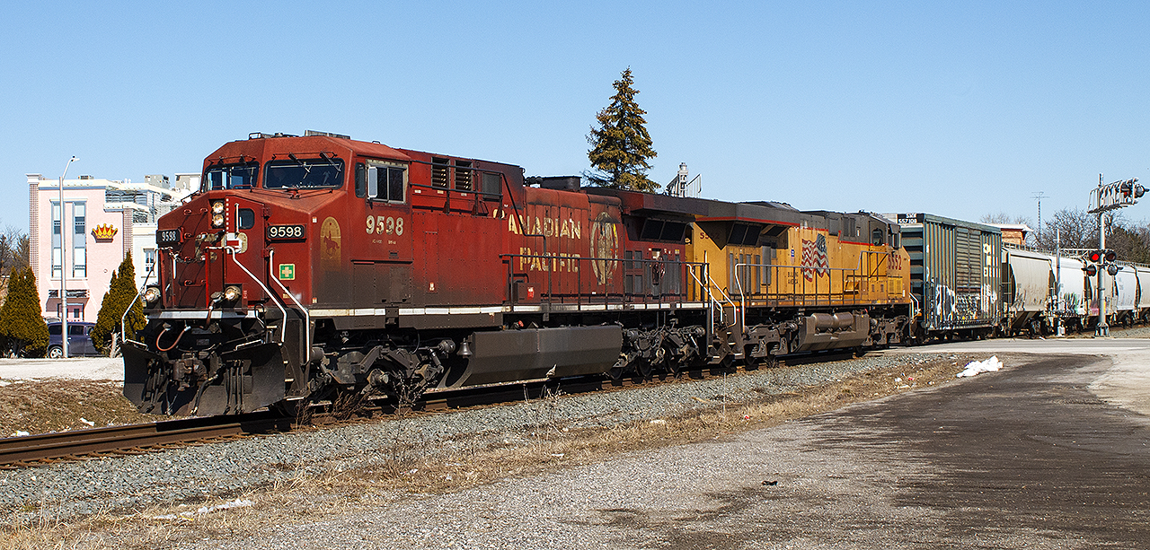 Beautiful, nearly an official Spring day, and thankful I had the camera one trip to the Missions Thrift Store to look around at some furniture. CP 9598 leads UP 5552, with a westbound freight crossing Wellington Street in downtown Chatham.


Note the small, and I use this term loosely, "white" logo near the nose of 9598. Thanks to fellow contributor  Luke Bellefleur,  this is the RCMP badge and motto. Of course, one would be hard pressed to see it due to the appearance of 9598. But, still nice to see on a gorgeous sunny day.