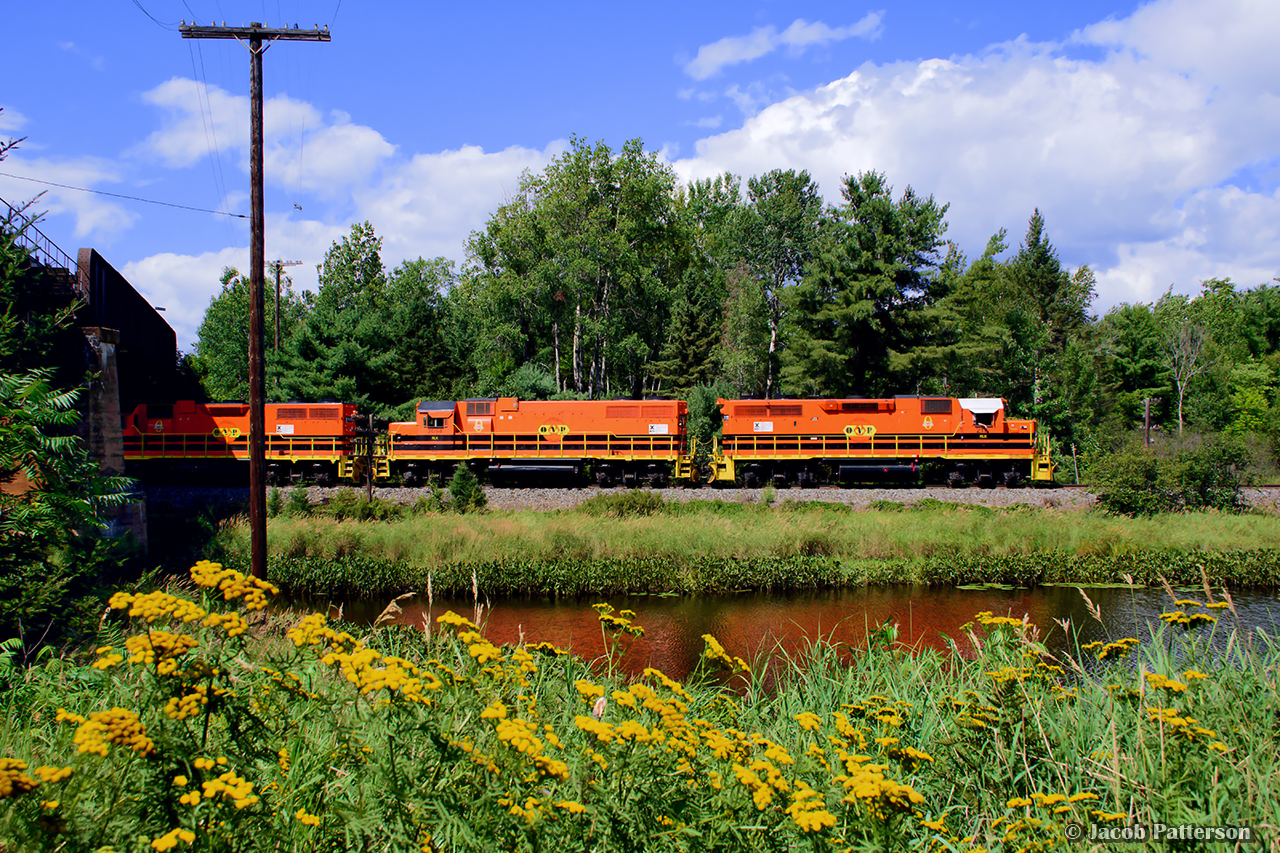 The tranquility along the shores of the La Vase River is briefly interrupted by squealing steel on this late summer afternoon. Ducking beneath CN’s Newmarket North sub, Ottawa Valley Railway F61 departs North Bay for the 85 mile run to Mattawa with 29 cars for Rayonier Advanced Materials’ mill in Temiscaming, Quebec.  A week after this photo, RYAM would announce the indefinite idling of the Temiscaming mill on account of 50% tariffs imposed by the American government.


The Kipawa Mill was constructed at Temiscaming circa 1918 - 1919 by the Riordon Pulp and Paper Company, which had also acquired the nearby 1888 Lumsden Sawmill.  The site would come under control of the Canadian International Paper Company (CIP) in 1925, and continue until 1972 when CIP would close the mill.  It was revived in 1973 under the name Tembec, a company largely founded by the mill's former employees, which ran until being bought out by Rayonier Advanced Materials in 2017.

Further information can be found in the 1975 National Film Board documentary Temiscaming, Quebec.