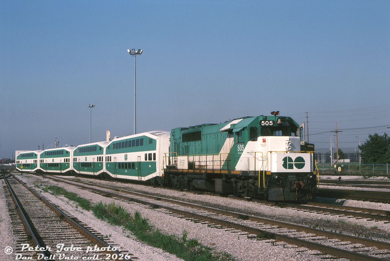 A short GO Transit consist lingers at the west end of Willowbrook Yard, made up of GO GP40TC 505 and four bilevels including a cab car. This consist is a little bit smaller than a regular revenue train, perhaps it was a special or test train for some occasion. The red K3L air horn suggests a swap by CP shop forces at some point, possibly while it was leased to CP in freight service. In the background, the tall chain-link fences of the Mimico Correctional Centre off Horner Avenue can be seen.

One of eight specially-built GP40TC (Toronto Commuter) locomotives dating from 1966, at this point in 1988 they were all on borrowed time. With new GMD F59PH units rolling off the assembly line in London, GO 505 and her siblings had already been put up for sale earlier that year in May, and would depart for Amtrak in October, hastily renumbered into their new numbers 192-199.

Peter Jobe photo, Dan Dell'Unto collection slide.