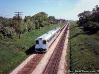 GO Transit self-propelled car 9826 and another sister car head westbound on the CN Kingston Sub through Scarborough, seen about to pass under the Woodrow Blvd. bridge on the stretch between Birchmount and Kennedy Rd. In the distance beyond Kennedy is Scarborough GO Station.
<br><br>
GO's nine self-propelled single-level cars (D700-D708, later 9825-9833) were intended for covering regular and off-peak service, with the idea that the rest of the Hawker Siddeley fleet could be converted to self-propelled cars if they proved to be reliable. But, due to ongoing reliability issues with the Rolls-Royce engines, they were eventually all depowered in the mid-70's and used as regular cab cars. 9826 (built as D701) was one of two built with a cab at each end, designated RTC-85SPD. It was sold to Ontario Northland in 1985 and converted into lunch-counter coach 701.
<br><br>
<i>Original photographer unknown, Dan Dell'Unto collection slide.</i>