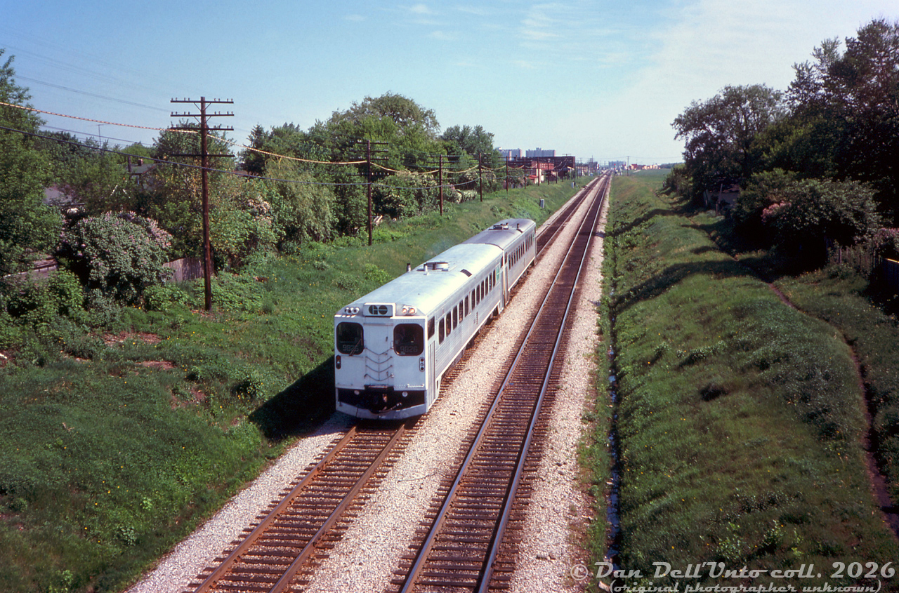 GO Transit self-propelled car 9826 and another sister car head westbound on the CN Kingston Sub through Scarborough, seen about to pass under the Woodrow Blvd. bridge on the stretch between Birchmount and Kennedy Rd. In the distance beyond Kennedy is Scarborough GO Station.

GO's nine self-propelled single-level cars (D700-D708, later 9825-9833) were intended for covering regular and off-peak service, with the idea that the rest of the Hawker Siddeley fleet could be converted to self-propelled cars if they proved to be reliable. But, due to ongoing reliability issues with the Rolls-Royce engines, they were eventually all depowered in the mid-70's and used as regular cab cars. 9826 (built as D701) was one of two built with a cab at each end, designated RTC-85SPD. It was sold to Ontario Northland in 1985 and converted into lunch-counter coach 701.

Original photographer unknown, Dan Dell'Unto collection slide.