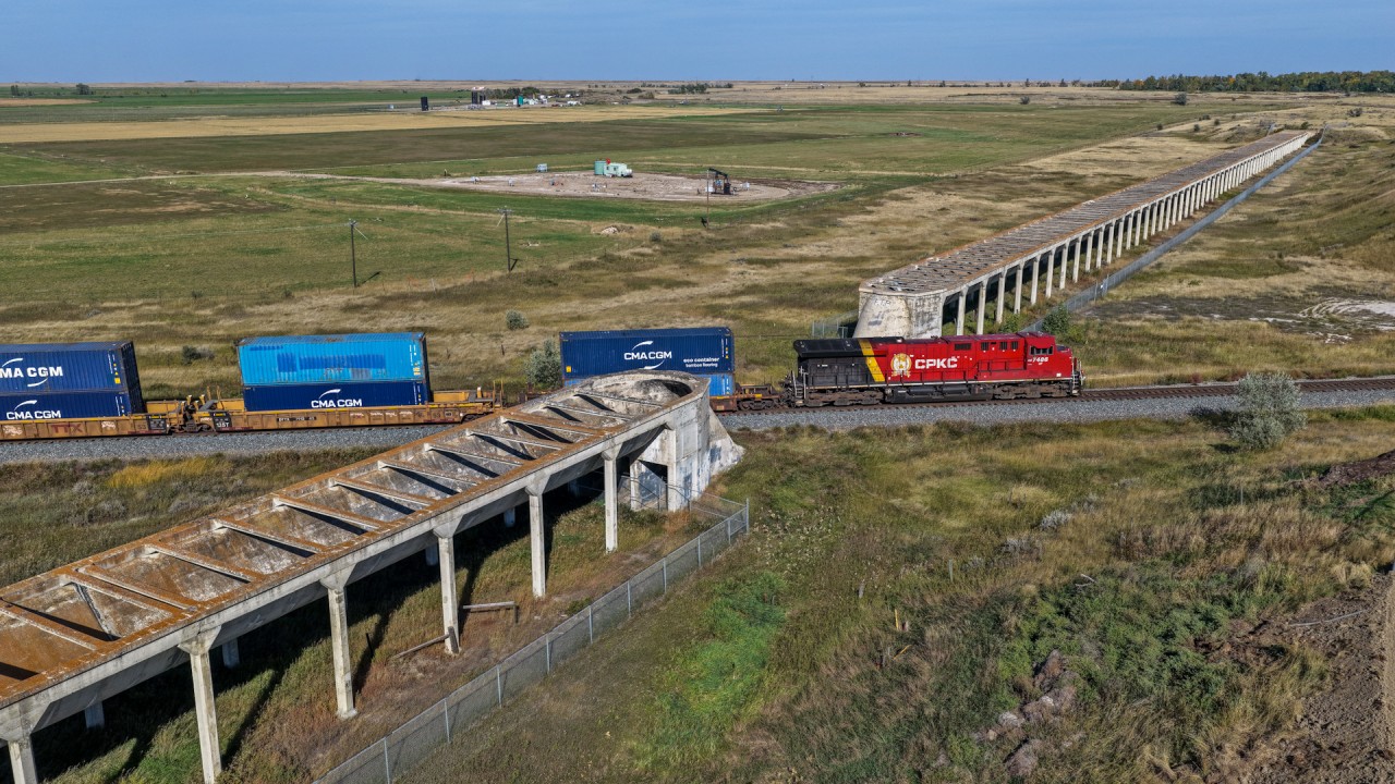 The Brooks Aqueduct was built between 1912 and 1914, to supply water to farmers from Newell Lake.  The CPR built the Aqueduct to encourage settlement in the area and it remained in service for around 30 years, however was prone to leaks and was eventually replaced by an elevated canal on a berm.  The Aqueduct is currently a protected historical site, although has had some sections removed over the years.  The location is easily accessible and trains still operate past this historical location.  CPKC 100-22 is one of the many daily trains that pass this location.