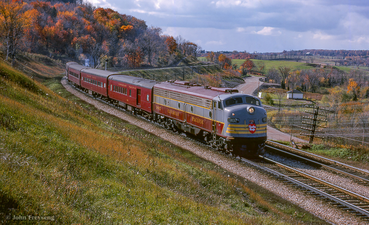 The weekend of October 23 & 24, 1965 saw the Upper Canada Railway Society run an excursion on each of the class one railways. The Saturday trip running on the Canadian Pacific behind CPR E8A 1802 departed Toronto Union station for Hamilton's TH&B Hunter Street station via the Oakville Sub, before heading up to Guelph Junction, Streetsville, and north to Orangeville before returning to Union Station. Here, the train snakes through the curves near the former station site of Christie, just east of the Kelso ski hill.

More of this excursion:
<a href=https://www.railpictures.ca/?attachment_id=52063Southbound at Cataract
Southbound at Inglewood

Scan and editing by Jacob Patterson.