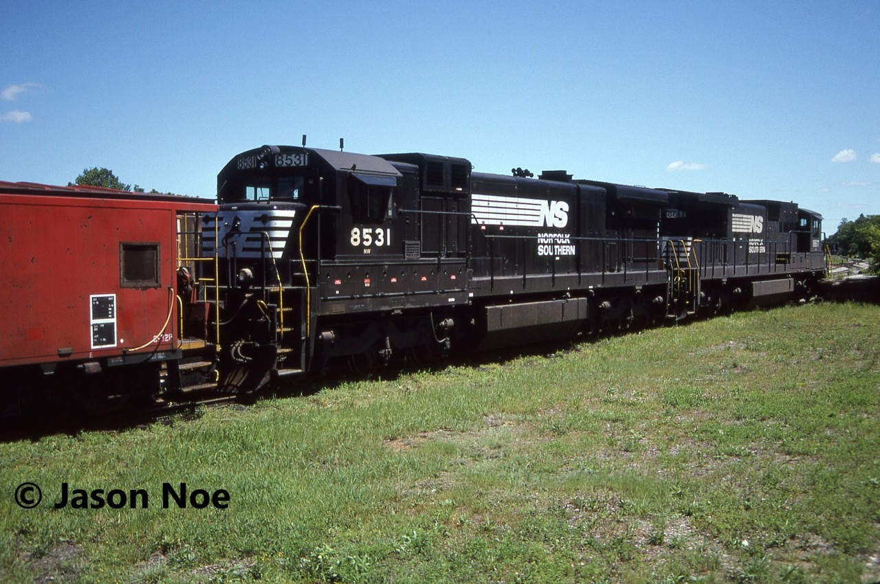 During a hot summer afternoon, Norfolk & Western caboose 555019 along with Norfolk Southern C39-8 8617 and C36-7 8531 await their next call to duty at the CN yard in St. Thomas, Ontario. Van 555019 was one of several NW cabooses assigned to Canada.