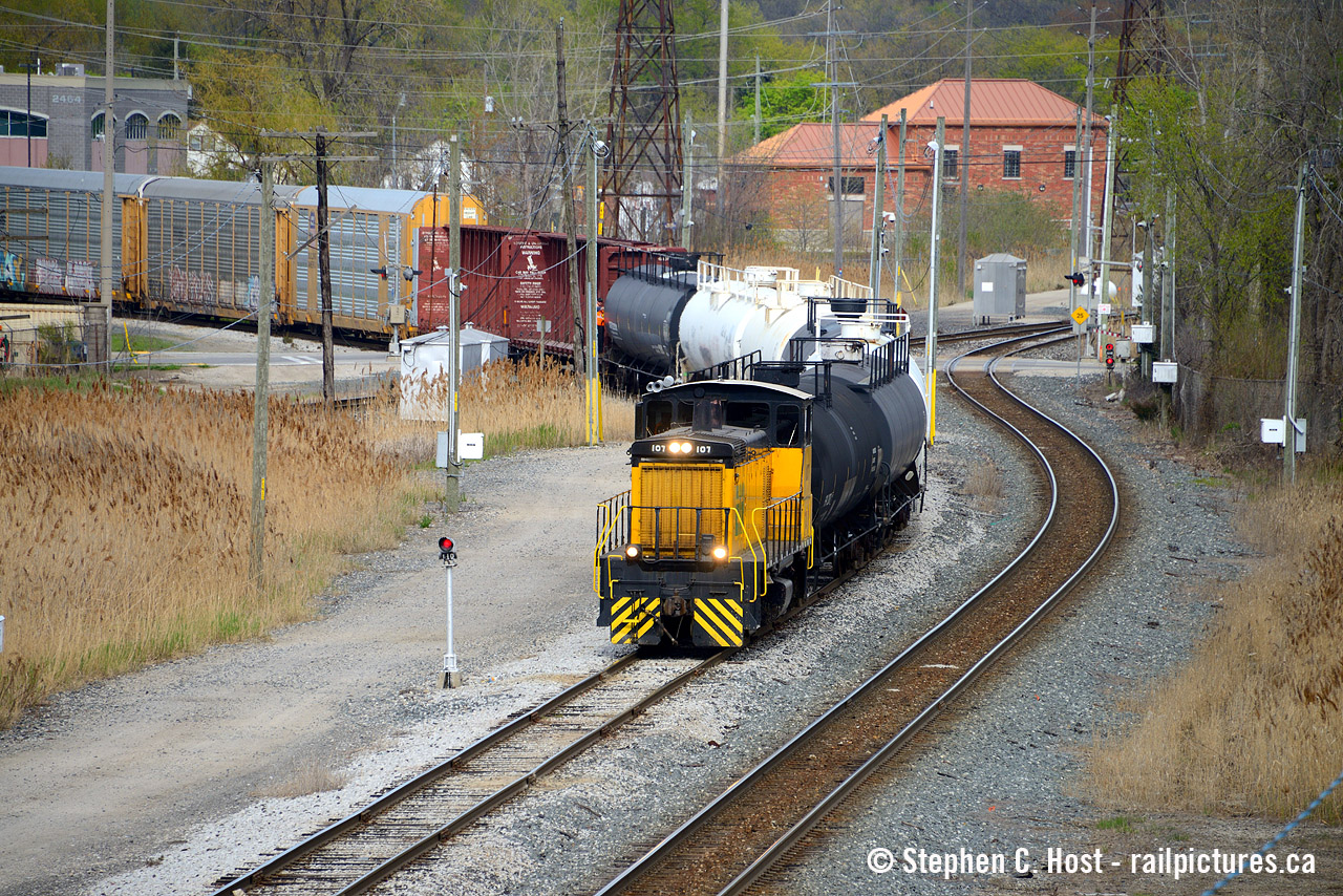 Pictured is the ETR's 1530 job crossing the CPKC Mainline, protected by the signal on a mast. Note the conductor a few cars back - the ETR folks work quick - they don't mess around. After switching cars near head office/walker yard, they brought a cut of cars directly to interchange with this feller riding all the way. Talk about terminal service! Note ETL 107 is a former EMD Demonstrator SW1500 former EMDX 113. What's the building in the background? is it related to customs or border protection?