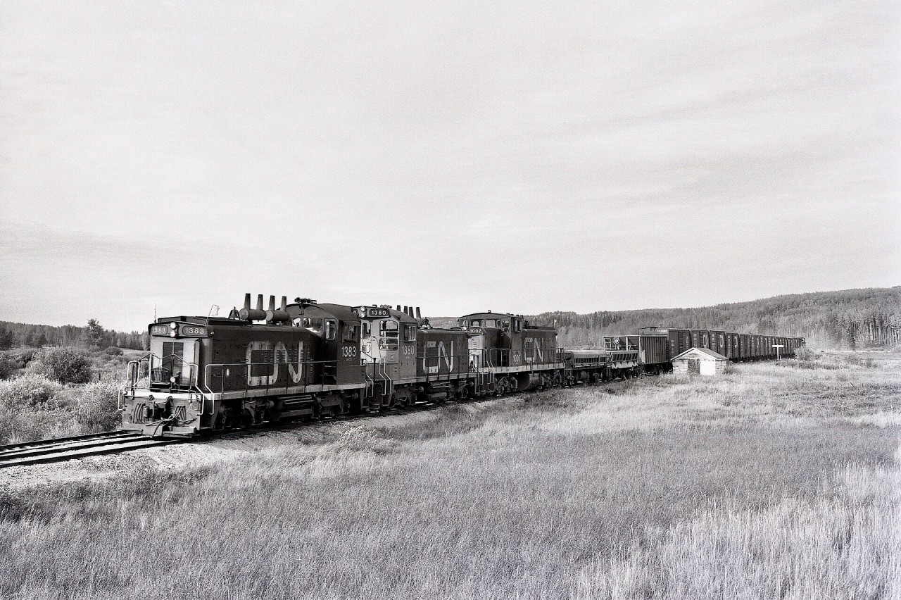 Southward from the north end of CN’s Athabasca subdivision at Athabasca, the line followed Tawatinaw Creek to start the trip back to Calder yard in Edmonton.  On Tuesday 1978-09-19 at 1649 MDT, CN 1383 + 1380 + 1007 trundled by the Station Name Sign and maintenance-of-way shelter at Tawatinaw.