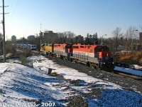 The day probably started out as any other Sunday, with word from the usual sources that GEXR was running an export special today with some good foreign merchandise heading to port, just released from the EMD/GMD London plant. So we made our way to downtown Brampton to frolic on the snowy hills of Sir Winston Churchill Park to wait for it to show. It was a balmy +5 and wasn't as cold as <a href=https://www.railpictures.ca/?attachment_id=60017><b>yesterday</b></a>, so that was nice.<br><br>Since there weren't that many wide-open spots downtown, we perched ourselves on our favourite little hill near the Centre St. underpass by the "new" CN Peel interlocking, decently wide-open and right across from the emergency department entrance behind the old Peel Memorial Hospital (established in stuffy 1925, just freshly closed at the end of October 2007), not far from Ardglen Drive (that had a reputation I didn't stick around to find out) and Trueman Street (also unsavoury). Lighting around 2:40pm in late November was "be happy this is what you get, it could be snowing".<br><br>After the CN RTC squeezed an unremarkable CN #398 through Peel, right on his tail were three of GEXR's best stray dogs of the pack, RLK GP35 2211 (ex-CP 5010), GP40 4096 (ex-CN 9306) and LLPX GP38-2 2236 (ex-LIRR 262) doing the honours of hauling the #432 "export special", made up of five shiny blue and white EMD GT36HCW units for Algerian National Railways/SNTF, and four white GT42CWRM "Class 66" units for Euro Cargo Rail in the UK (I <a href=http://www.railpictures.ca/?attachment_id=16369><b>shot so many of those</b></a> back then that they became somewhat boring), plus EMD idler flats. My notes indicate the exact units today were SNTF 060DS02, 060DS03, 060DS04, 060DS05, 060DS06, EWS (ECR) 077006, 077007, 077008, and 077009 (the ECR's were lettered but unnumbered, so their order may be scrambled for confusion). It still wasn't wide-open enough here to get the whole train, but we did get <a href=http://www.railpictures.ca/?attachment_id=11932><b>individual shots</b></a> of all the units.<br><br>After 432's passing, we made our way to the VIA/GO station downtown on foot for a CN #399 and #148, before dining on Brampton's finest pizza west of the 410 (Gusto's, tell them Dan sent you) and made our way back home.