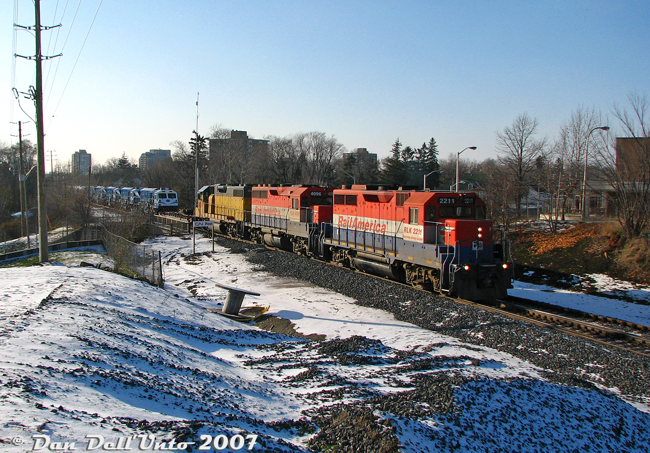 The day probably started out as any other Sunday, with word from the usual sources that GEXR was running an export special today with some good foreign merchandise heading to port, just released from the EMD/GMD London plant. So we made our way to downtown Brampton to frolic on the snowy hills of Sir Winston Churchill Park to wait for it to show.

Since there weren't that many wide-open spots downtown, we perched ourselves on our favourite little hill by the Centre St. underpass by the "new" CN Peel interlocking, decently wide-open and right across from the emergency department entrance behind the old Peel Memorial Hospital (established in stuffy 1925, just freshly closed at the end of October 2007), not far from Ardglen Drive (that had a reputation I didn't stick around to find out) and Trueman Street (also unsavoury). Lighting around 2:40pm in late November was "be happy this is what you get, it could be snowing".

After the CN RTC squeezed an unremarkable CN #398 through Peel, right on his tail were three of GEXR's best stray dogs of the pack, RLK GP35 2211 (ex-CP 5010), GP40 4096 (ex-CN 9306) and LLPX GP38-2 2236 (ex-LIRR 262) doing the honours of hauling the #432 "export special" and its five shiny blue and white EMD GT36HCW units for Algerian National Railways/SNTF, and four white GT42CWRM "Class 66" units for Euro Cargo Rail in the UK, plus EMD idler flats. The exact units today were SNTF 060DS02, 060DS03, 060DS04, 060DS05, 060DS06, EWS (ECR) 077006, 077007, 077008, and 077009 (the ECR's were lettered but unnumbered, so their order may be scrambled for confusion). It still wasn't wide-open enough here to get the whole train, but we did get individual shots of all the units.

After 432's passing, we made our way to the VIA/GO station downtown on foot for a CN #399 and #148, before dining on Brampton's finest pizza west of the 410 (Gusto's, tell them Dan sent you) and made our way back home.