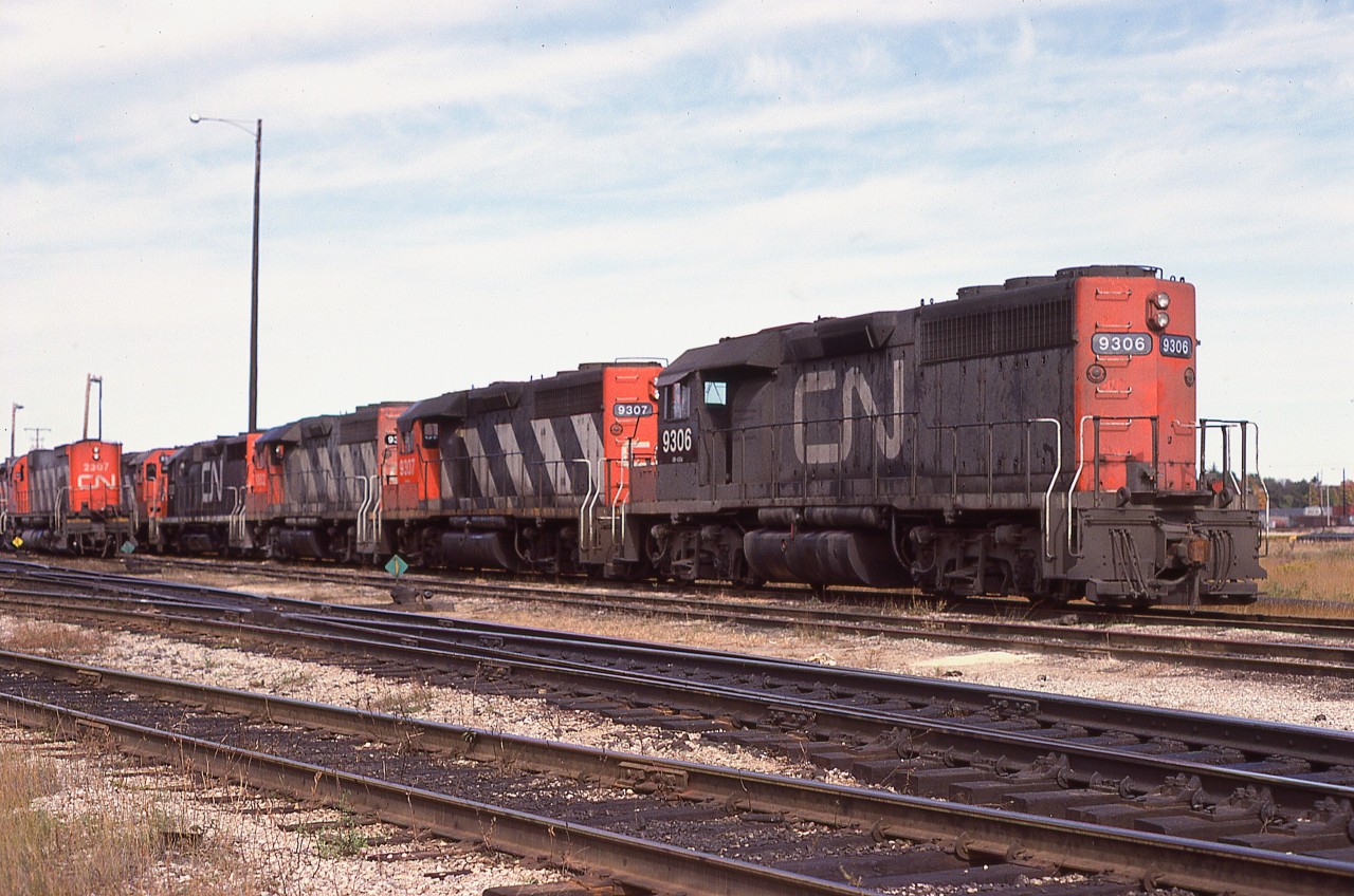 Dearly beloved, we are gathered here together.......... well not quite... actually, these CN  GMD GP40s are collected in town for their official renumbering.
Seen in a row in the yard are CN 9306, 9307, 9302, 9310 and others. They had previously toiled in the 4000 series. Built in 1966/67, they were retired or sold by 1998.