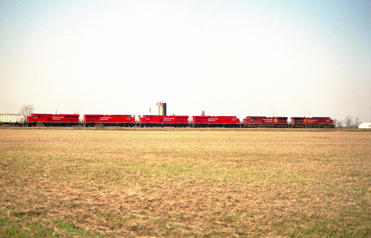 For us seasoned guys, it seems that the grubby locomotives on CP have been around forever. Well, not quite, but close. The introduction of the AC4400CW grime carriers in 1995 was bad enough, but the delivery of the ES44AC units (in 2005) unfortunately carried on the filthy CP tradition as well.  Pity, because they looked nice new.
It has been 21 years since the new 8700 series hit the scene.  In this image, new 8721, 8722, 8723 and 8720 have arrived in Canada behind 9607 and 9760.
The scene is just a hair north of mile 23 where the train is just across the river out of the Welland Yard. Photo taken using Mamiya 645 with Fuji PRO400H film. I believe farm buildings obscure this angle now.