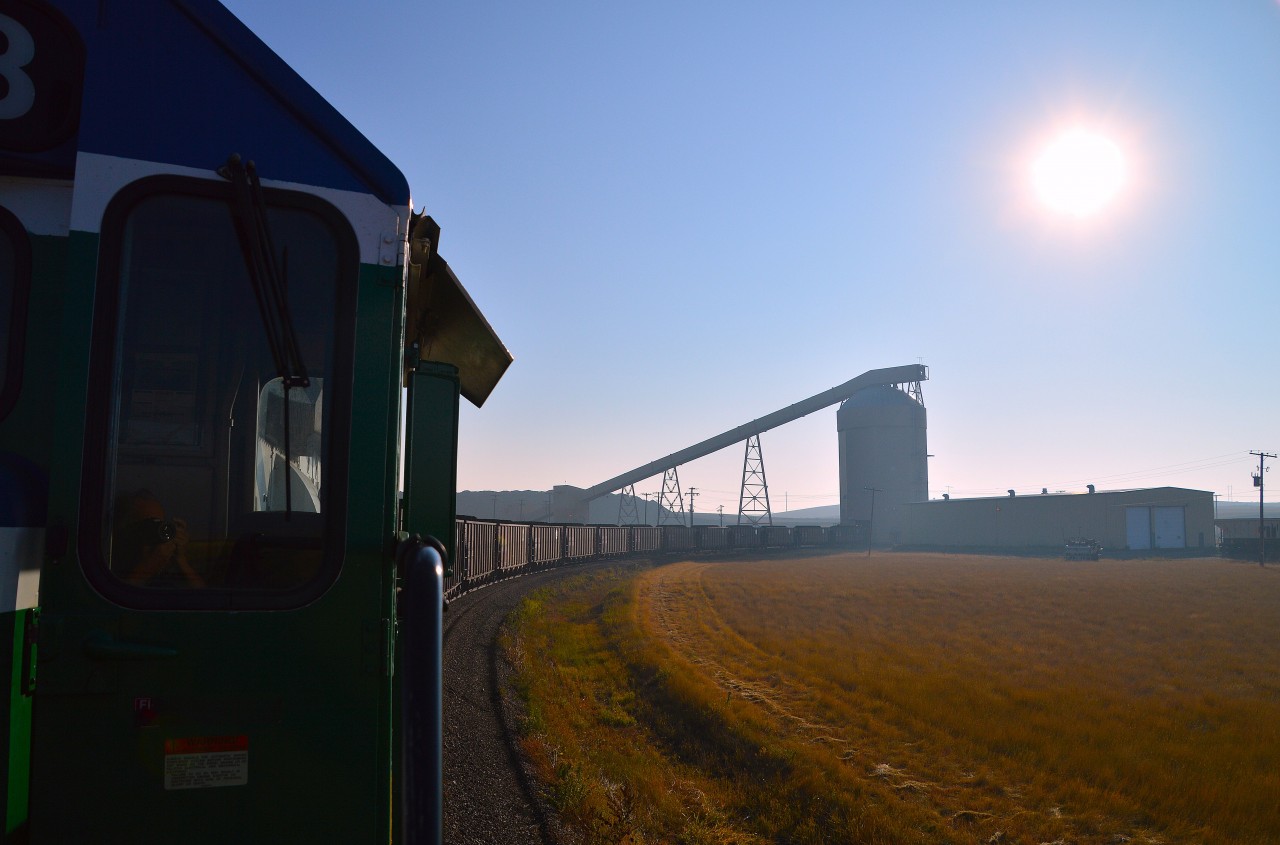 It was rather invigorating to be invited up into the cab of PRMX 6973 for a run down to the Poplar River Power Generating Station, about 12 miles distant to the south.  In this image, we are loading and almost ready to depart the Poplar River Coal Mine. Not much out there to see, typical Saskatchewan grasses and a few gravel grade crossings until you get to the Hwy 18 crossing and the Generating Plant. Coronach itself, a village of about 650 people, lies a bit to the west.
The whole operation here is under control of Westmoreland Mining, LLC, and there is a chance it may be shut down by 2030. Tours of the mine itself are available in the summer months two days a week. Call ahead.