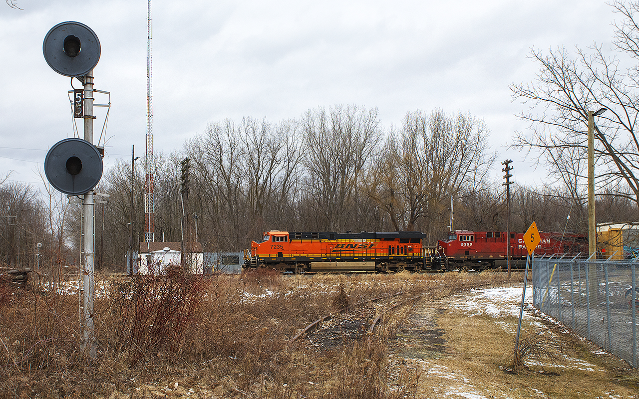 Perfect 'permacrud' type of day. I decided to check out the former C&O / CSX station grounds. So much change, since I was here 20 years before. Standing on the southern portion of the wye, last used back when these two roads exchanged traffic, this auto rack train snuck up on me. Led by a wonderfully coloured BNSF leader, I believe this was train 235.


NOTE: Both north and south signals,  although unused, still stand protecting where the diamond once was between the CP and CSX. Of course, mounds of dirt were piled on either side of this once busy C&O Sub. No. 2. The little Chatham depot once stood to the left, but out of frame. The red brick platform was still in place then, as was most sidings in the CP yard.