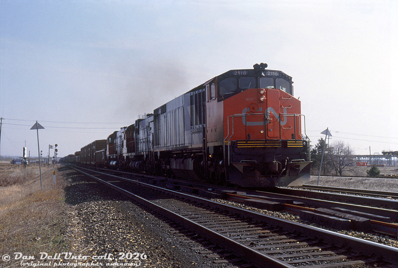 CN HR616 2116, one of Bombardier's short-lived line of "High Reliability" (hah) locomotives, leads a 2000-series C630M and 2300-series M636 on a westbound freight on the Halton Sub, seen crossing Torbram Road and advancing through Halwest (the junction between CN's Halton and Weston Subs) on the Brampton-Missisauga border. The Halton-Weston connecting track can be seen to the right of the 2116, as well as the overhead crane in the background for the MakSteel facility next to Malport Yard.
On the left, out of view in the field next to the photographer, there was once a lumber yard back in the 70's called Lampton Lumber with a siding, that has since all but vanished. There were once about four lumber yards in this immediate area of Bramalea back in the more rural days, all with rail sidings: Lampton Lumber here,  Weston Road Lumber on the other side of the tracks to the south (still present today as Weston Forest Products), Malton Lumber (ex-Reid & Co./Lauder Boake Lumber) off Bramalea Road immediately south of Halwest, and Cashway Lumber (L.W. Larkin) that used to be at the present Bramalea GO station site. The encroachment of one-stop-shop big box building improvement stores such as Aikenheads, Home Depot and Lowes in the 90's no doubt contributed to the decline of the local small-town lumber yards.

Original photographer unknown, Dan Dell'Unto collection slide.

(This unlabeled slide (possibly taken by the late Keith Hansen) had no location given, but sometimes one just recognizes a spot).