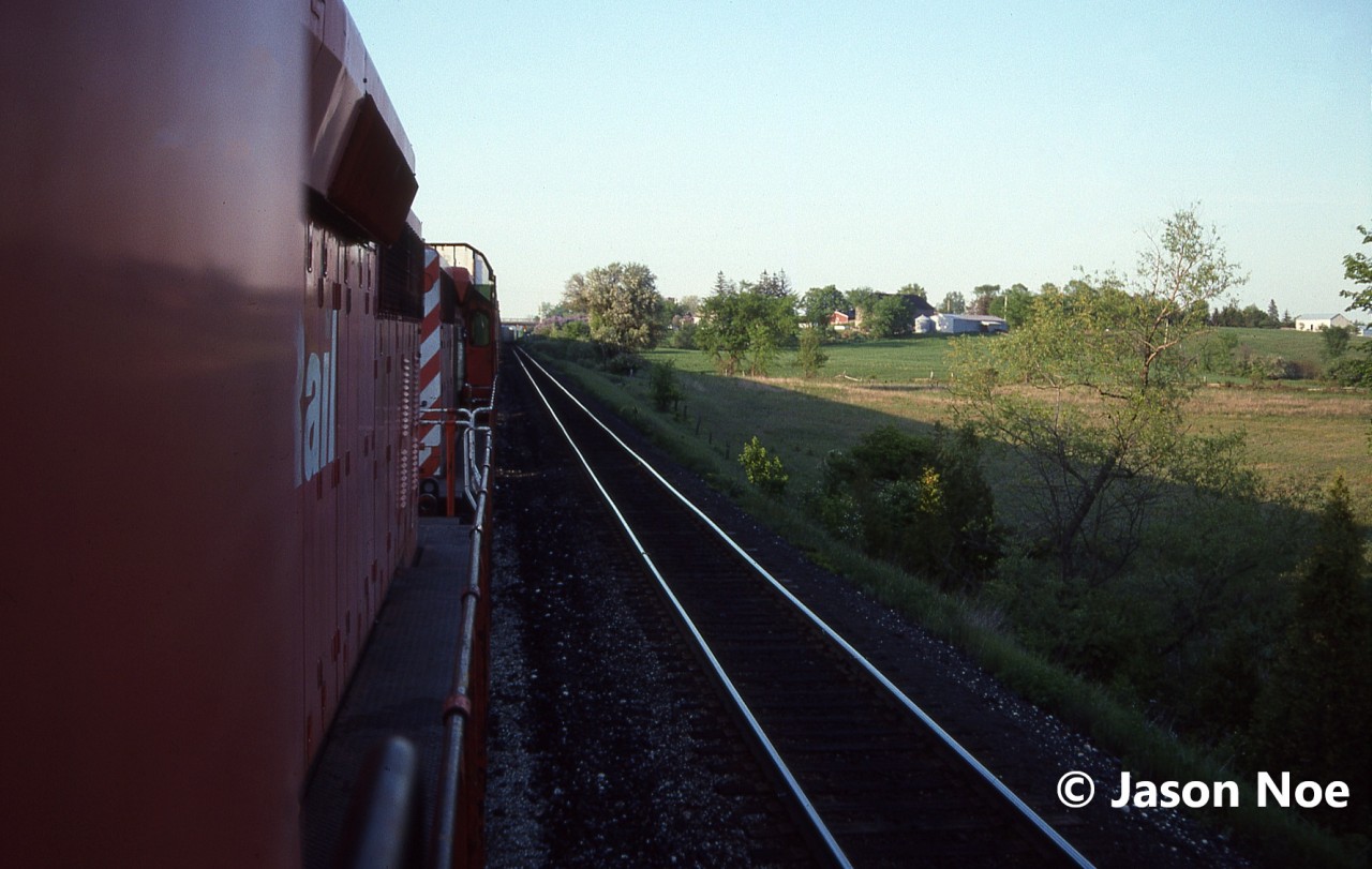 Leaning out of the cab of 5649 west, here is the view captured looking back as 737 enters the siding at Puslinch, Ontario on the Galt Subdivision for a meet with an eastbound. At the time, 737 was a dedicated auto train and on this evening the friendly crew had invited a friend and I along for a cab ride to the top of Orrs Lake hill from Puslinch. The consist included SD40-2’s 5649 and 5682.