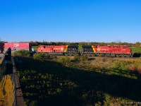 As the sun dips towards the horizon, the shadow of Lovekin's wooden bridge is cast towards CPKC's Belleville Sub, where intermodal 118 is viewed thundering towards Montreal.