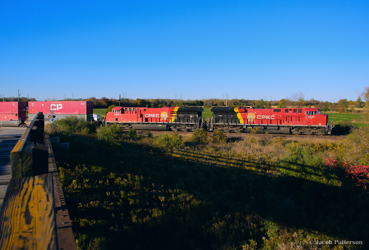 As the sun dips towards the horizon, the shadow of Lovekin's wooden bridge is cast towards CPKC's Belleville Sub, where intermodal 118 is viewed thundering towards Montreal.