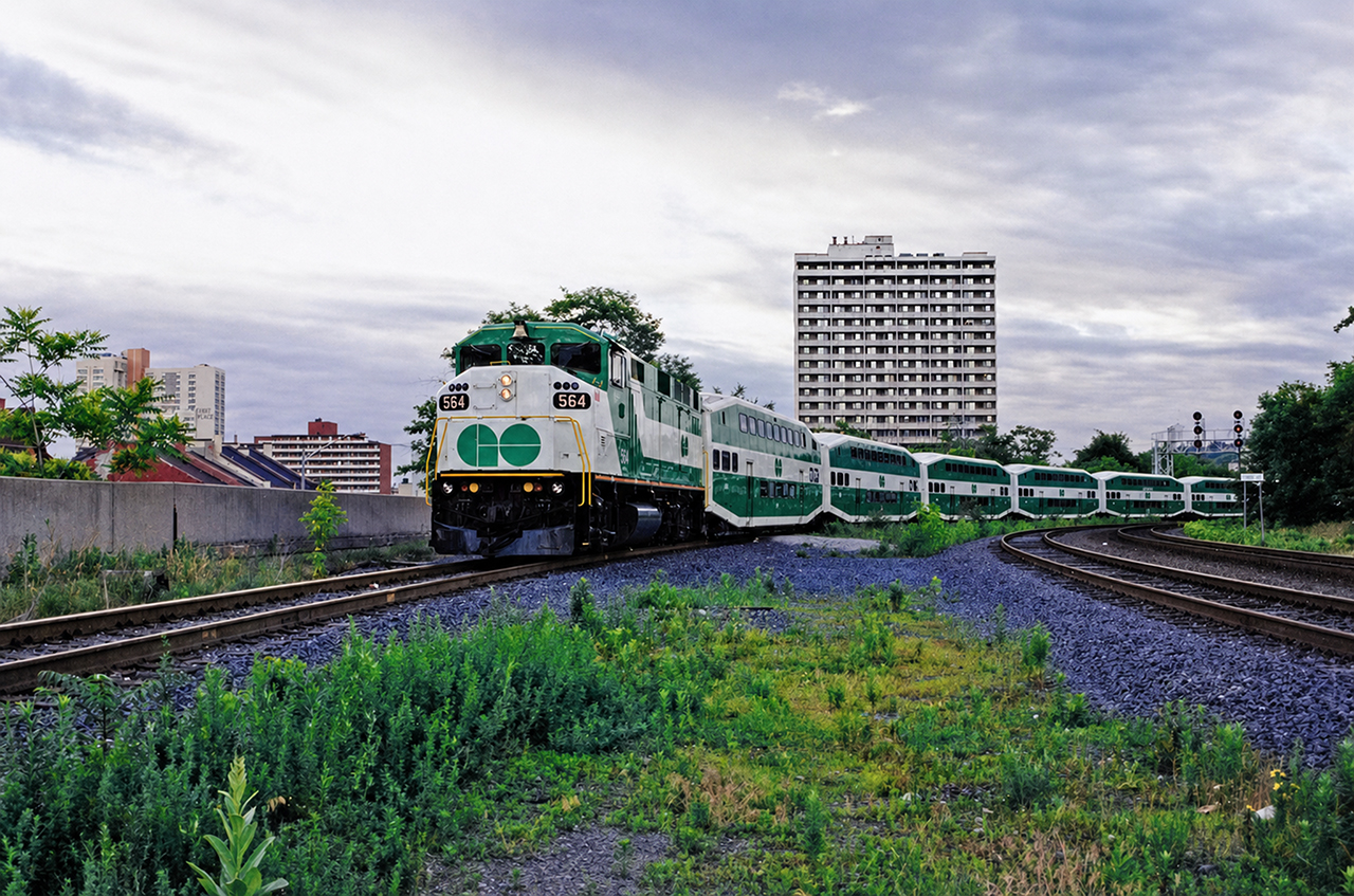 GO F59PH #564 brings a string of empty bilevels around the curve and into Hamilton GO Centre on a June morning in 1998. At the time, GO's three morning trains from Hamilton would be brought from Willowbrook Yard, two of them coupled together. The 564's train would be the last to depart on this day and as such, it was pulled past the platform to the east until the first train of the morning departed and vacated the inside track. Today, there is a storage yard for GO trains at this location and this equipment move is no longer necessary.