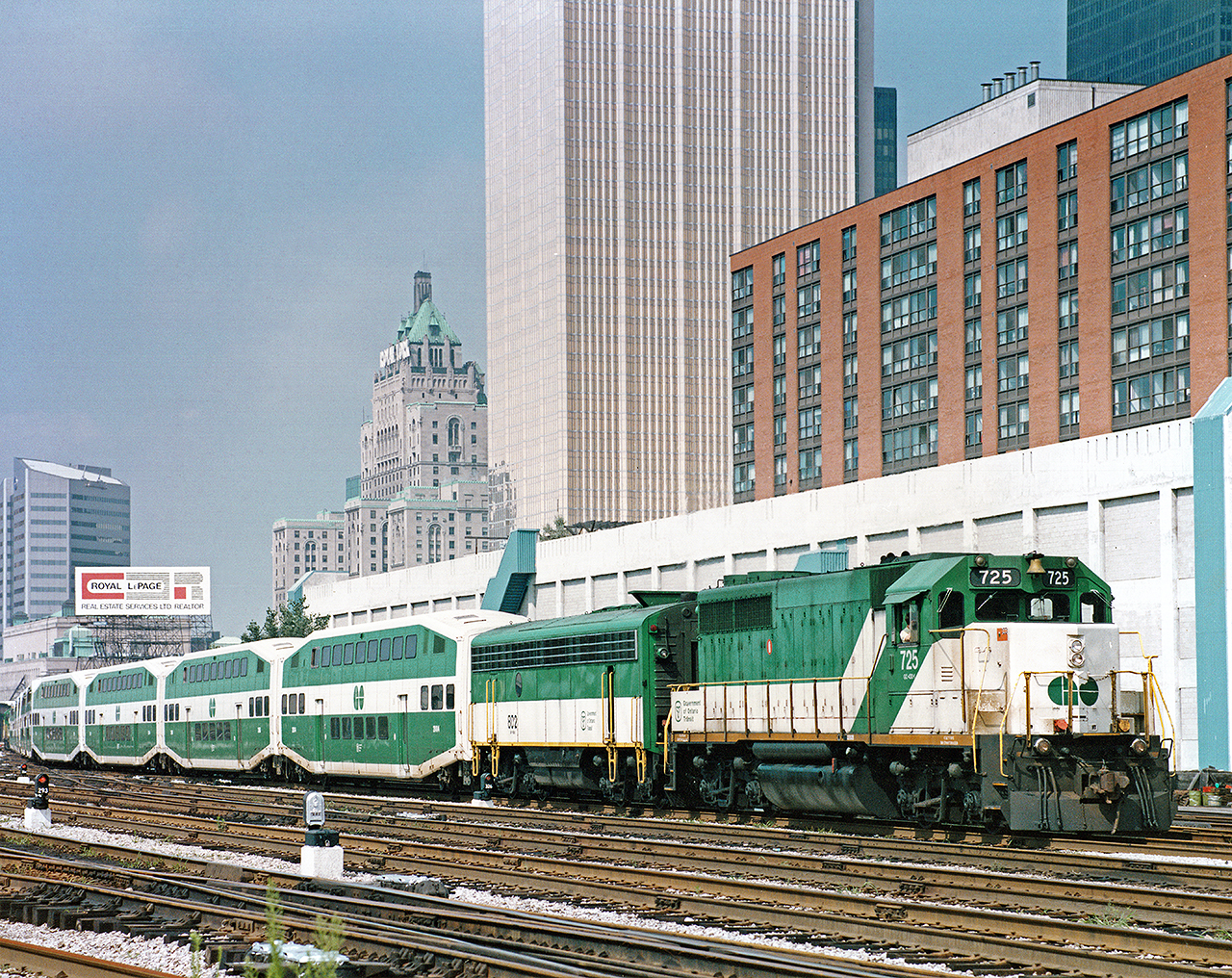 GO GP40-2M #725 leads F7 APU #802 and a long string of bilevels with another GP40 on the west end out of Toronto Union Station. Photo from my collection- a print I purchased at the Toronto train show years ago. Original photographer is Dave Shaw, per written info on rear of print.