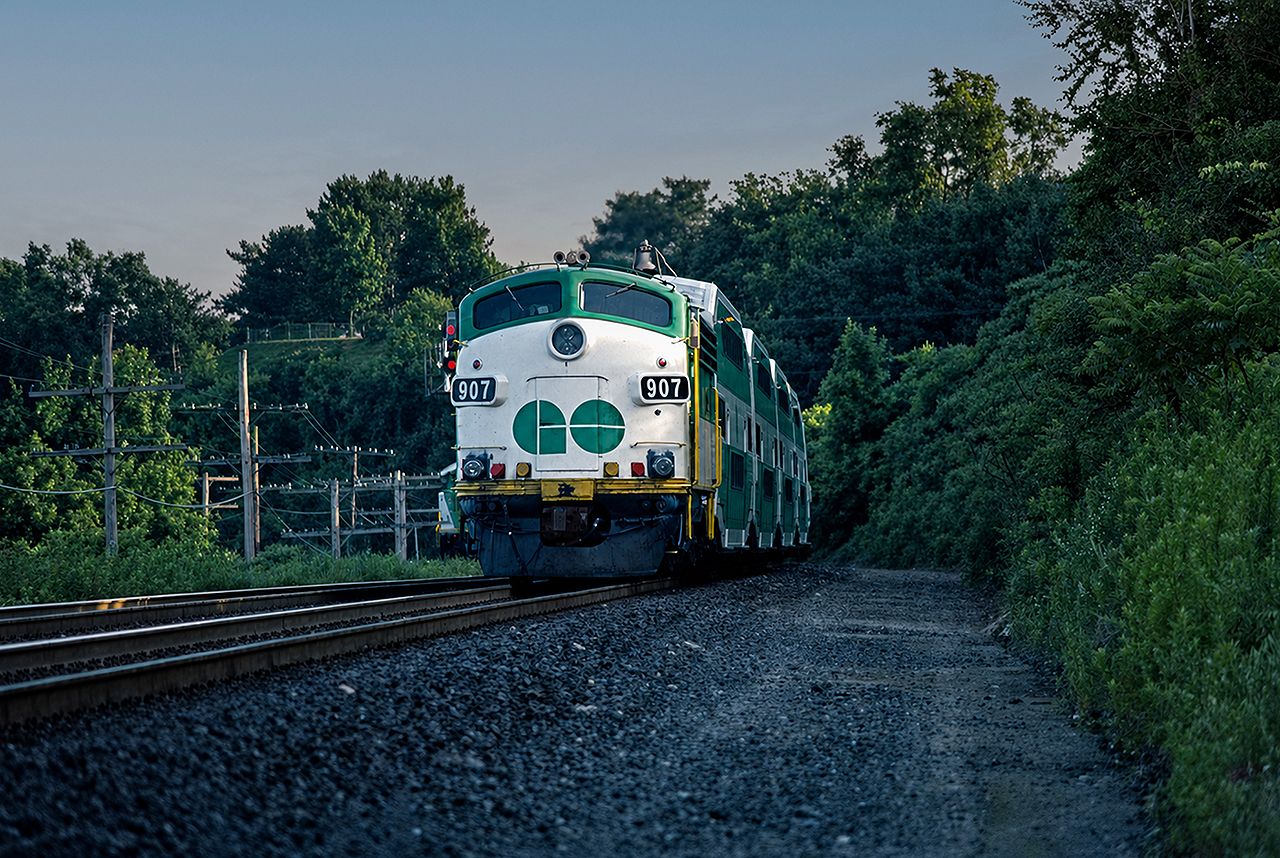 GO FP7 APCU 907 trails an evening rush hour train through Bayview from Toronto Union Station to Hamilton, with recently installed ditch lights. These Auxiliary Power Control Units (APCU) were common on GO Transit throughout the 1980s into the early 1990s, as the GP40-2W and GP40-2M locomotives lacked HEP power generators of their own. Scanned slide from GO564 collection and restored, original photographer unknown.