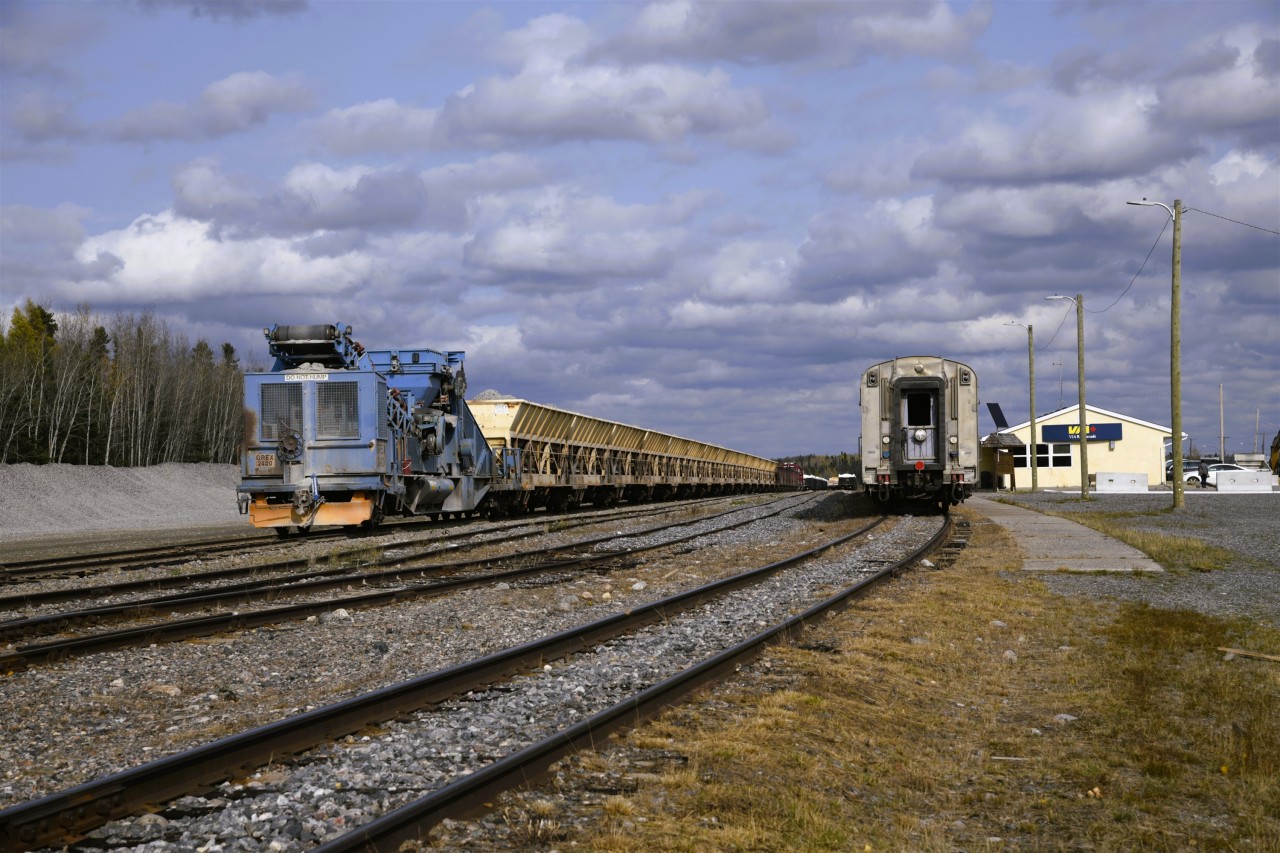 Work train at the ready  
GREX 2400 is the power and unloading conveyor car for the loaded ballast train ready to head out and dump more stone for the continuing rehabilitation of HBR's tracks to the port in Churchill, MB. 
Having taken the VIA 693/692 round-trip from Winnipeg to Churchill twice a year for the past four years I have witnessed the incredible improvements in the roadbed and other infrastructure all along the line. 
My next trip is coming up on October 19-25, 2026 and I will be looking to snap some more interesting sights along the remote route for posting to RP. 
At the right of the frame, sleeping car VIA 8202 Chateau Bienville brings up the tail-end 'paddle' and rear-facing white light on VIA 693 The Hudson Bay during its scheduled multi-hour station stop in Thompson.