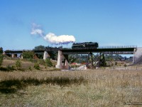 The weekend of September 13 - 15, 1963 marked a massive undertaking by the Upper Canada Railway Society, a 692.2 mile excursion from Toronto - Ottawa - North Bay - Temagami - Toronto, with seventeen coaches behind CNR 6167. With the train having run overnight from Toronto - Ottawa on the 13th, the train turned west and departed the nation's capital early on the 14th, running across northern Ontario to North Bay. 6167 would be removed at North Bay, with ONR FP7s handling the train to Temagami overnight. The consist returned to North Bay on the morning of the 15th, with 6167 taking over once again for the return to Toronto.  Further information can also be found in the <a href=https://railwaypages.com/upper-canada-railway-society-ucrs-and-its-publications>December 1963 UCRS news letter.</a>

<br><br>About 40 miles after <a href=https://www.railpictures.ca/?attachment_id=59949>the previous runpast,</a> CNR 6167 has cut off from the excursion to take on coal and water, and is seen making a reverse move over the Muskrat River bridge.  Below the bridge, and to the right of the tender, note the white milepost of the CNR Locksley Subdivision, which should be mile 20, as "National Junction" would be located at mile 20.2, off to the right closer to town.  The Locksley Sub ran 21.1 miles from Golden Lake, and a connection to the CNR Renfrew Sub, north to Pembroke, ending at a downtown station.  CNR was permitted to abandon the Locksley Sub from Golden Lake to mile 19.5 in 1960, and mile 19.5 - mile 20.01 in 1963.  The remaining mile was used as an industrial spur.

<br><br>Pembroke was served by another CNR station on the mainline, a bit east of this location.  Del Rosamond shot <a href=https://www.railpictures.ca/?attachment_id=34364>an eastbound there in 1958.</a>

<br><br><i>Scan and editing by Jacob Patterson.</i>